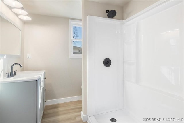 full bathroom with baseboards, walk in shower, wood finished floors, and vanity