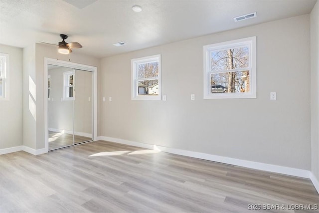 unfurnished bedroom with visible vents, baseboards, light wood-type flooring, and a closet