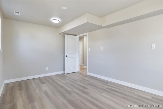 spare room with light wood finished floors, visible vents, and baseboards