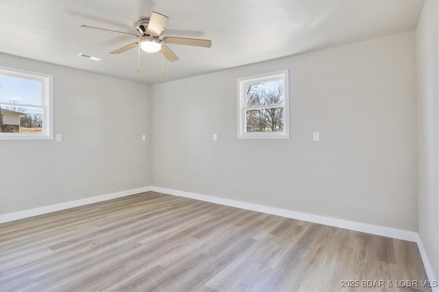 unfurnished room with visible vents, plenty of natural light, baseboards, and wood finished floors