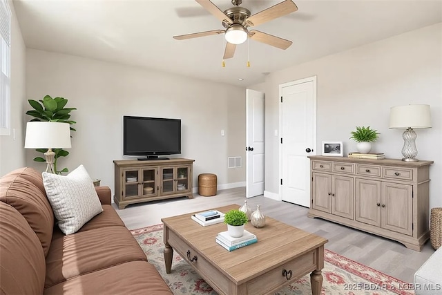 living room with visible vents, light wood-style flooring, baseboards, and a ceiling fan