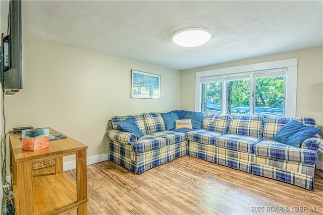 living area with a textured ceiling, baseboards, and wood finished floors