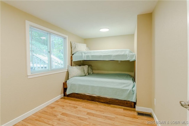 bedroom with wood finished floors, visible vents, and baseboards