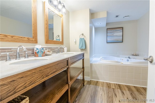 full bathroom featuring wood finished floors, a sink, a bath, and decorative backsplash