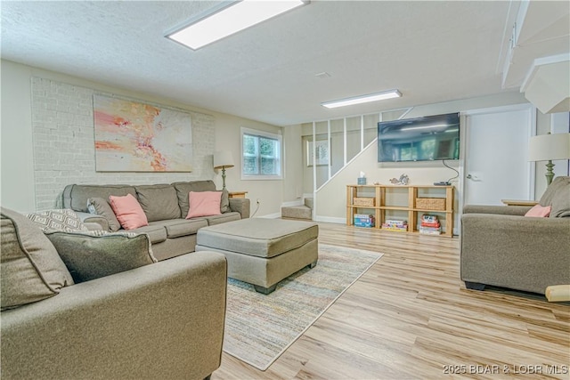 living area with a textured ceiling, stairway, light wood-type flooring, and baseboards