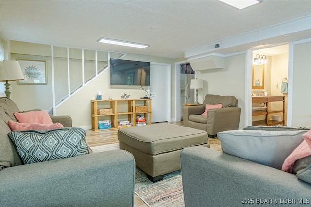 living room with visible vents, stairway, and wood finished floors