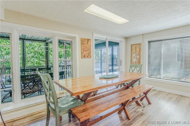 dining space with a textured ceiling, baseboards, and wood finished floors