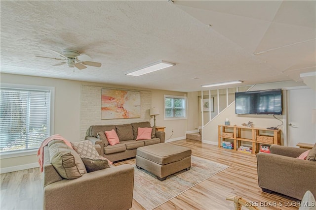 living room with light wood-type flooring, baseboards, stairway, and a textured ceiling