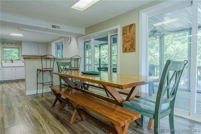 dining room with light wood-type flooring, visible vents, and a textured ceiling