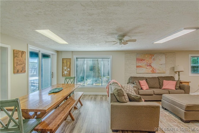 living room with a textured ceiling, baseboards, and wood finished floors