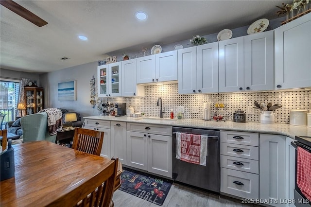 kitchen featuring wood finished floors, a sink, dishwasher, tasteful backsplash, and glass insert cabinets