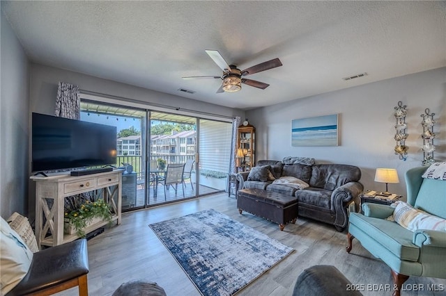 living area featuring a textured ceiling, wood finished floors, and visible vents