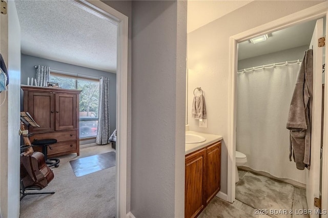 bathroom featuring a textured wall, toilet, a shower with curtain, a textured ceiling, and vanity