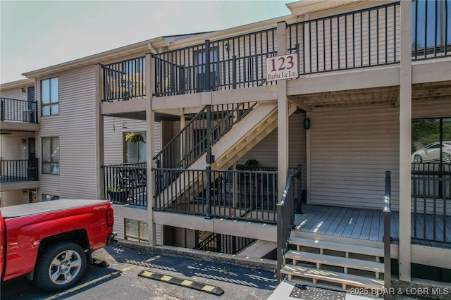 view of building exterior with uncovered parking and stairway