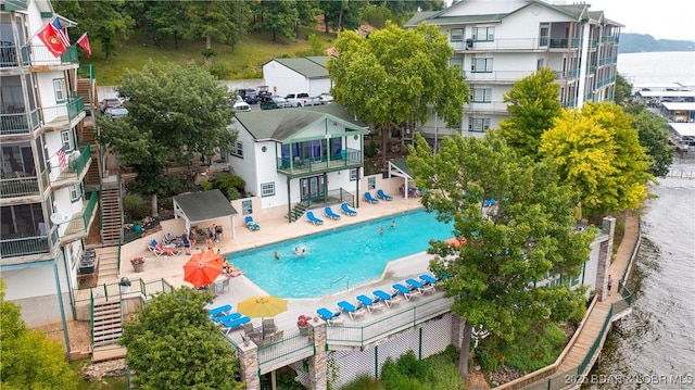 community pool featuring a water view, a patio area, and stairs