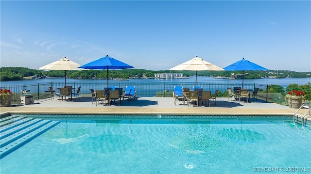 community pool with a water view, a patio area, and fence