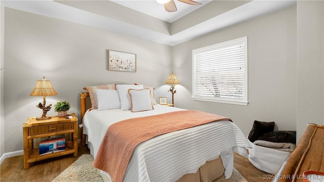 bedroom with a ceiling fan, baseboards, and wood finished floors