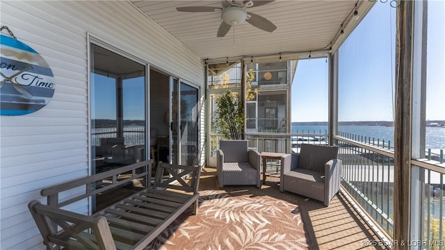 sunroom with a ceiling fan and a water view