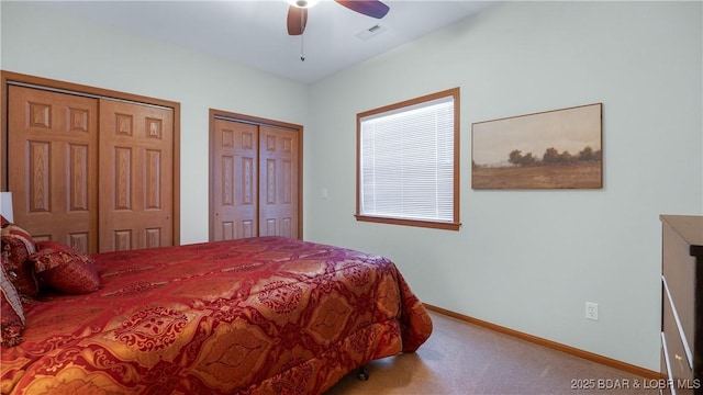 bedroom with visible vents, baseboards, ceiling fan, carpet flooring, and multiple closets