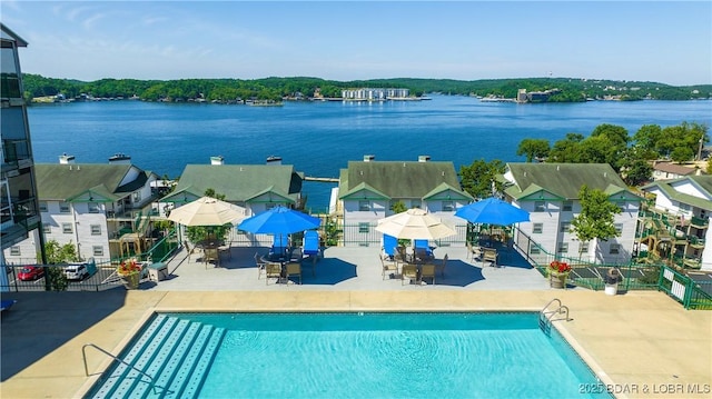 community pool featuring a patio area, fence, and a water view