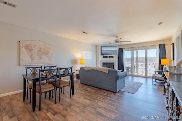 living area featuring baseboards, a fireplace, visible vents, and wood finished floors