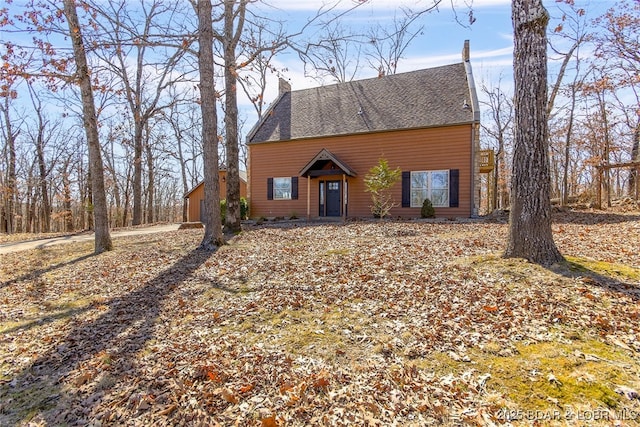 rustic home featuring a chimney and roof with shingles