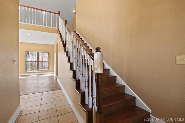 stairway with tile patterned flooring, a high ceiling, and baseboards