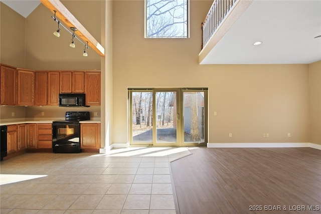 kitchen with black appliances, a high ceiling, light countertops, and baseboards