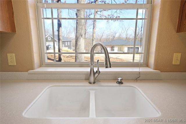 details featuring a textured wall, a sink, and light countertops