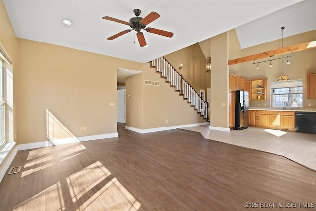 unfurnished living room featuring light wood-type flooring, visible vents, stairway, and baseboards