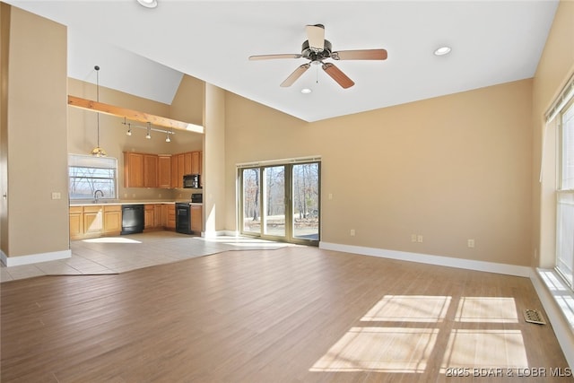 unfurnished living room featuring baseboards, a sink, and light wood-style floors