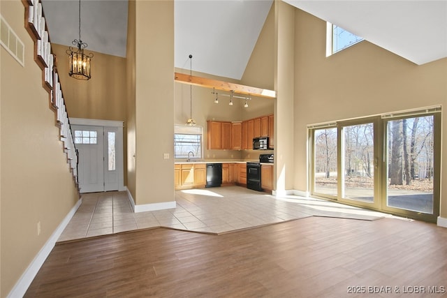 foyer with light wood-type flooring, a towering ceiling, baseboards, and a notable chandelier