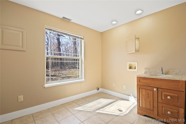 laundry room with hookup for a washing machine, cabinet space, visible vents, a sink, and baseboards