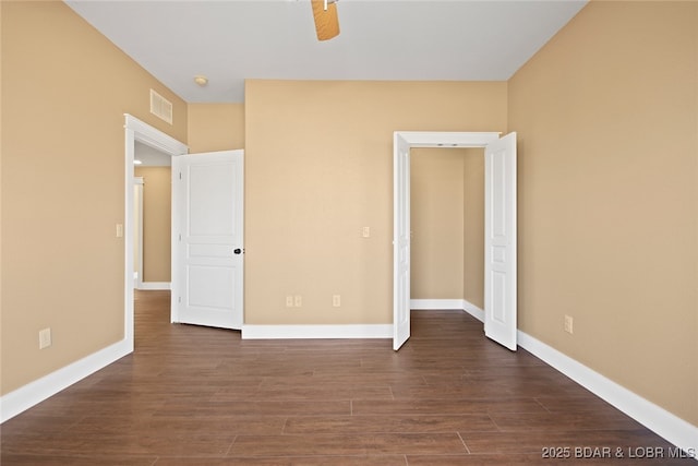 unfurnished bedroom with dark wood-style flooring, visible vents, ceiling fan, and baseboards