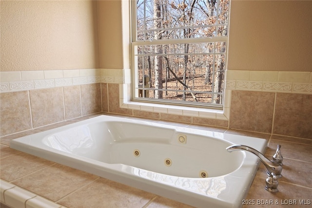 bathroom with a tub with jets and a textured wall