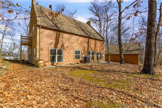 back of house featuring central AC, a chimney, and a balcony