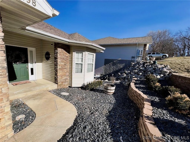 view of side of property with roof with shingles