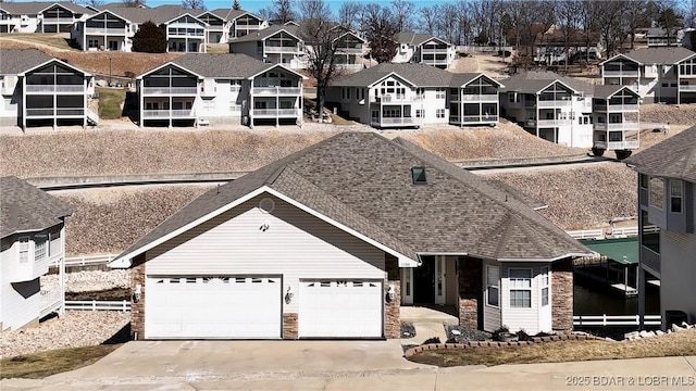 view of front of property with a residential view, stone siding, roof with shingles, and driveway