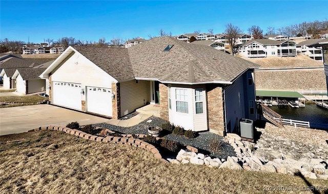 single story home with a shingled roof, concrete driveway, a residential view, an attached garage, and central AC