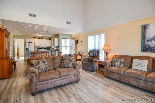 living room featuring track lighting, visible vents, and light wood-style flooring