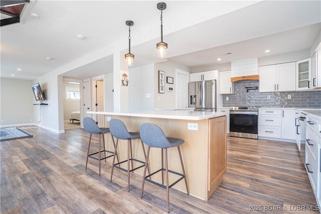 kitchen featuring stainless steel appliances, premium range hood, dark wood-type flooring, backsplash, and a center island