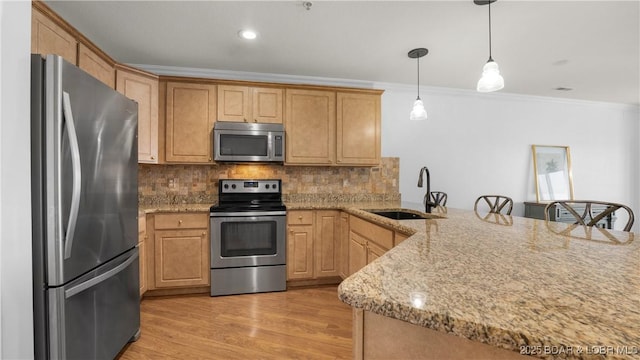 kitchen with crown molding, decorative backsplash, appliances with stainless steel finishes, light wood-style floors, and a sink