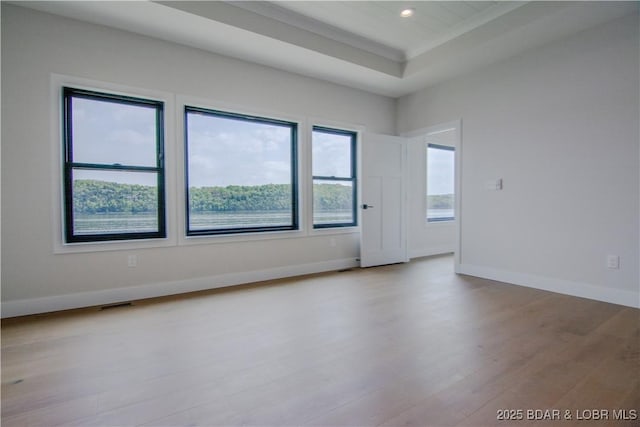 empty room with visible vents, baseboards, wood finished floors, a tray ceiling, and recessed lighting