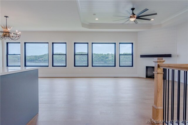 unfurnished living room with plenty of natural light, a fireplace, a raised ceiling, and wood finished floors