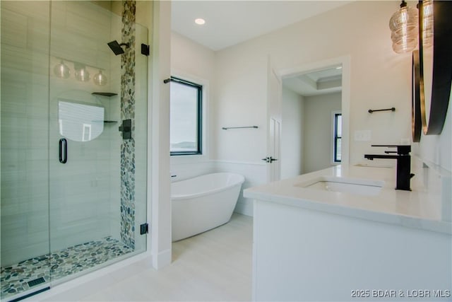 bathroom featuring double vanity, a stall shower, a sink, and a soaking tub