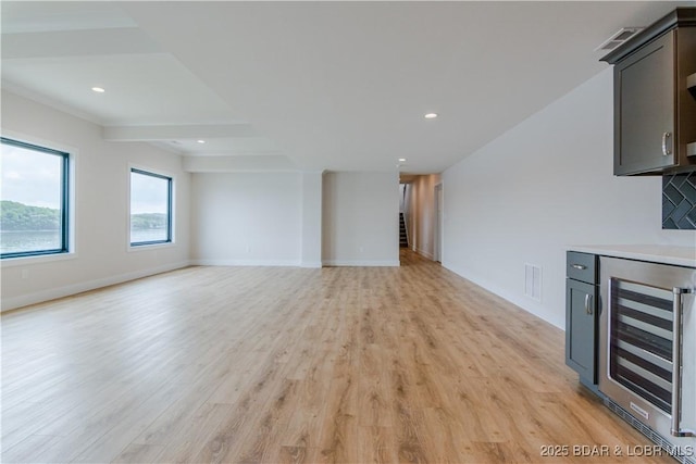 unfurnished living room with baseboards, wine cooler, recessed lighting, and light wood-style floors