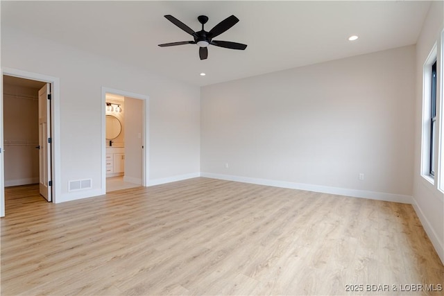 unfurnished bedroom with light wood-type flooring, baseboards, visible vents, and a walk in closet