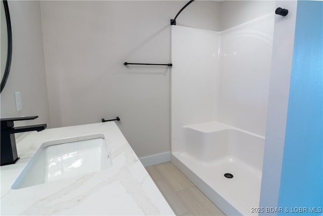 full bath with a shower, vanity, and baseboards