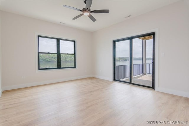 unfurnished room with a ceiling fan, light wood-style flooring, and baseboards