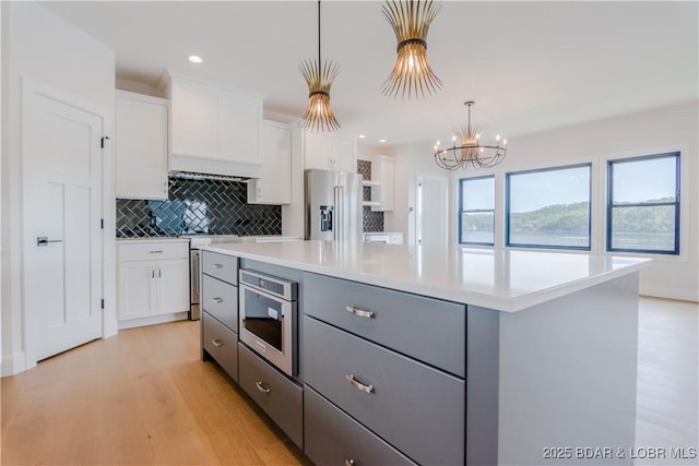 kitchen featuring stainless steel appliances, light countertops, white cabinets, and gray cabinetry